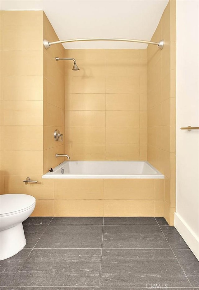 bathroom featuring toilet, tiled shower / bath combo, and tile patterned flooring