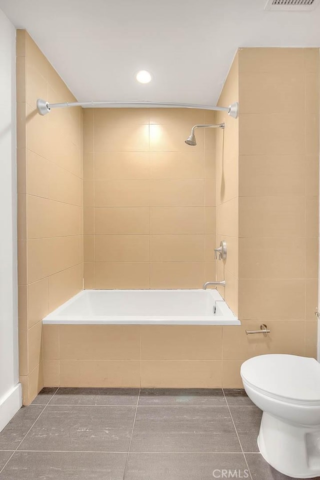 bathroom with toilet, tile patterned flooring, and tiled shower / bath combo