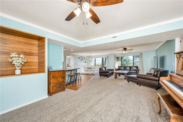living area with visible vents, carpet, ceiling fan, and baseboards