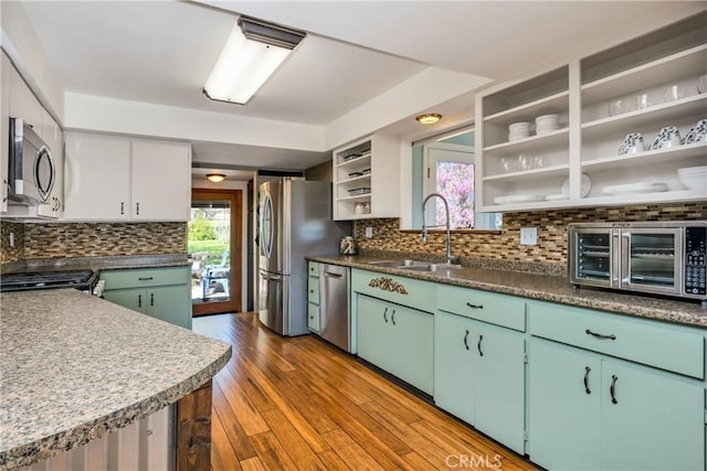 kitchen featuring plenty of natural light, a sink, open shelves, and stainless steel appliances