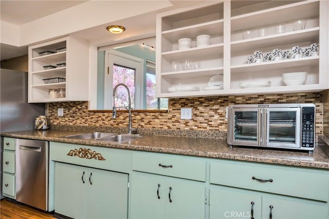 interior space with stainless steel dishwasher, open shelves, a sink, and dark countertops