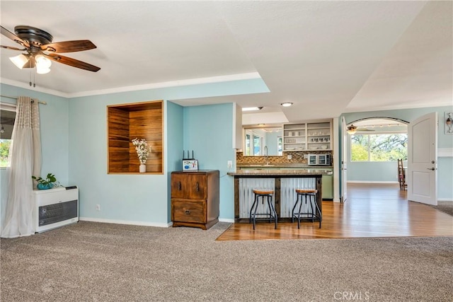 kitchen with carpet floors, baseboards, backsplash, and a ceiling fan
