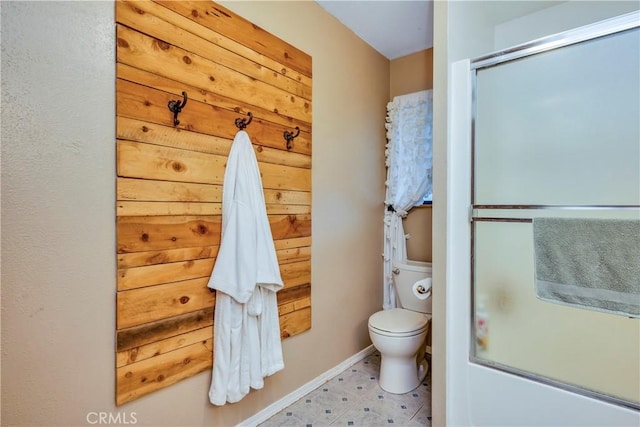 bathroom featuring baseboards, combined bath / shower with glass door, and toilet