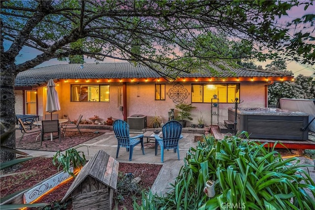 back of property with a patio, a hot tub, stucco siding, and a tile roof
