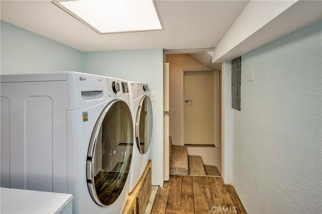 clothes washing area featuring laundry area, washer and clothes dryer, electric panel, and hardwood / wood-style floors