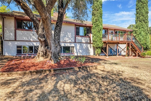 back of property featuring a deck, stairs, and stucco siding