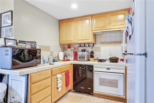 kitchen with light tile patterned flooring, sink, tasteful backsplash, white appliances, and tile countertops