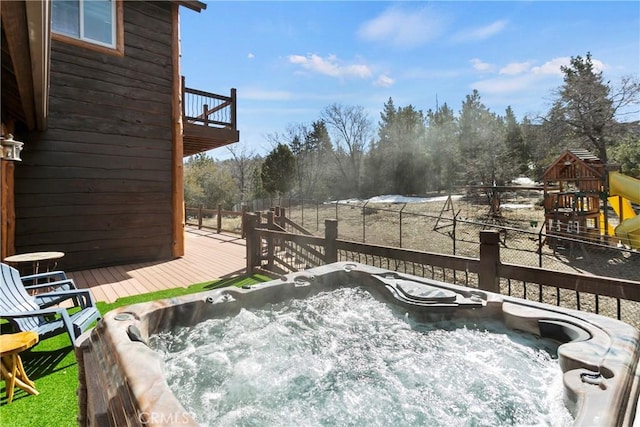 wooden deck with a playground and a hot tub