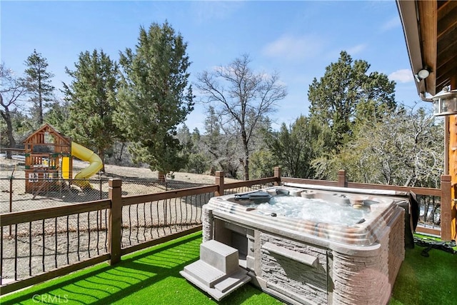 wooden terrace featuring a playground and a hot tub