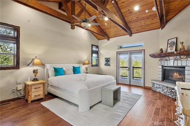 bedroom with ceiling fan, access to outside, wood-type flooring, a stone fireplace, and wooden ceiling