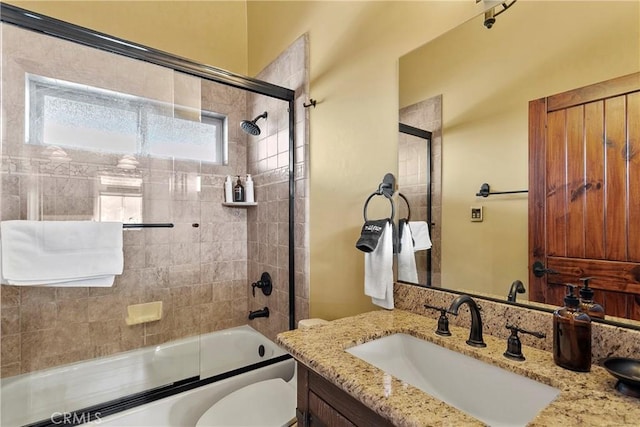 full bathroom featuring toilet, bath / shower combo with glass door, and vanity