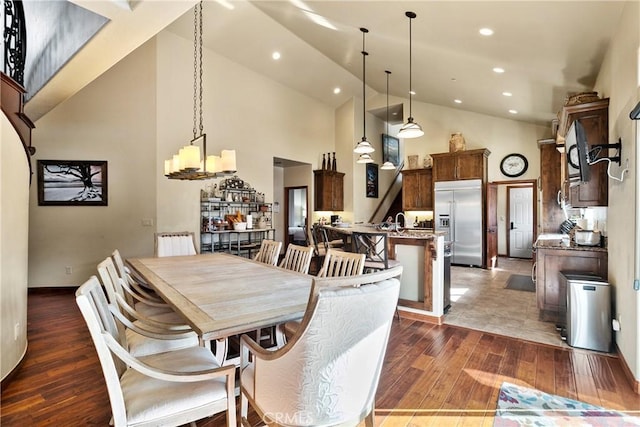 dining room with dark wood-type flooring, a chandelier, and high vaulted ceiling