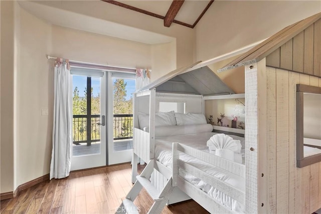 bedroom featuring access to exterior, hardwood / wood-style flooring, wooden walls, and lofted ceiling with beams