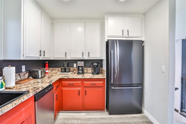 kitchen featuring light hardwood / wood-style floors, light stone countertops, white cabinetry, and appliances with stainless steel finishes