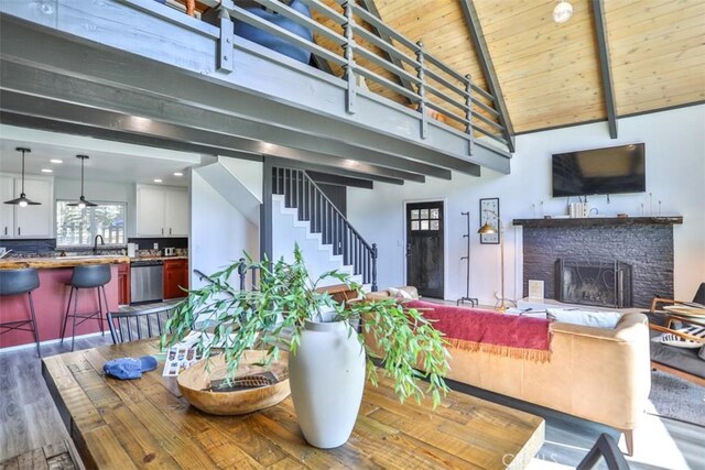 dining area with a brick fireplace, wood-type flooring, beamed ceiling, wood ceiling, and high vaulted ceiling