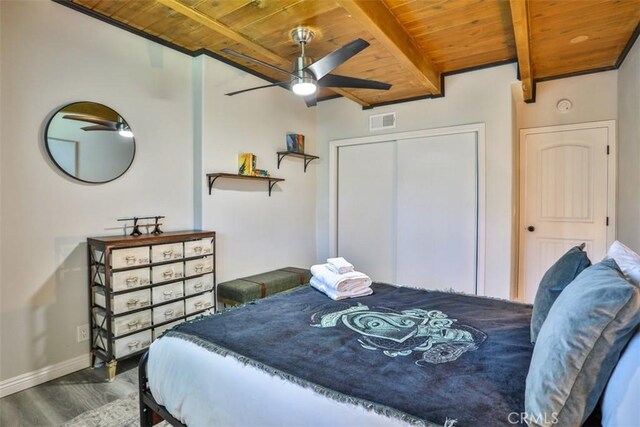 bedroom featuring wood ceiling, beamed ceiling, dark hardwood / wood-style floors, a closet, and ceiling fan