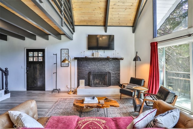 living room featuring wooden ceiling, beam ceiling, wood-type flooring, and a stone fireplace