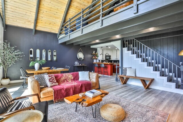 living room featuring hardwood / wood-style flooring, wooden ceiling, a high ceiling, and beamed ceiling