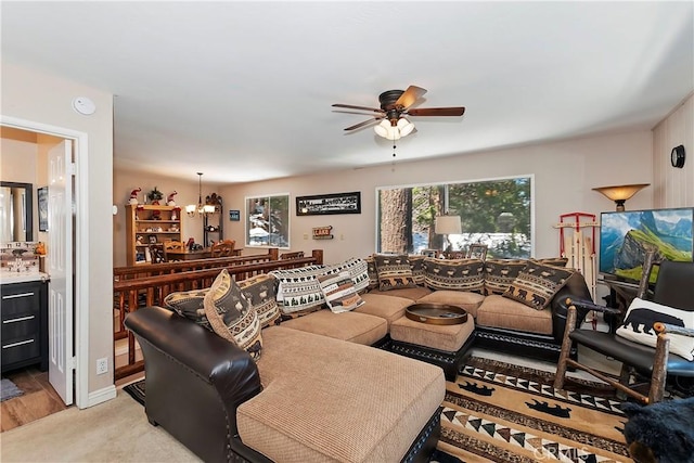 carpeted living room with ceiling fan with notable chandelier