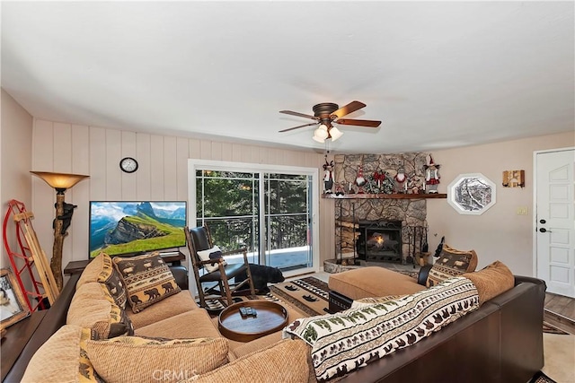 living room featuring hardwood / wood-style floors, ceiling fan, and a stone fireplace