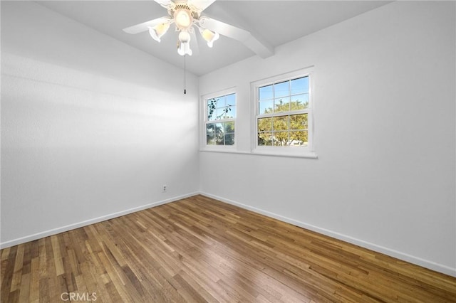 empty room featuring hardwood / wood-style flooring, beamed ceiling, and ceiling fan