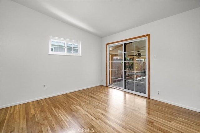 spare room with light wood-type flooring, vaulted ceiling, and ceiling fan