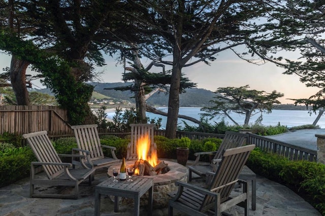 patio terrace at dusk with a water view and an outdoor fire pit