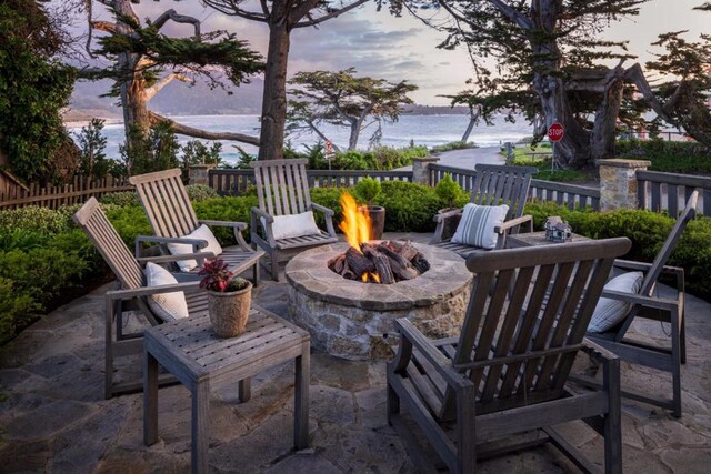 patio terrace at dusk with a water view and an outdoor fire pit