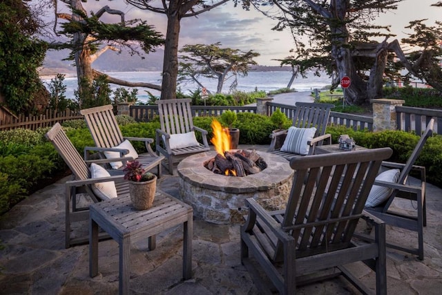 patio terrace at dusk featuring a fire pit and a water view