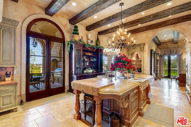 kitchen featuring an island with sink, beamed ceiling, french doors, wooden counters, and sink