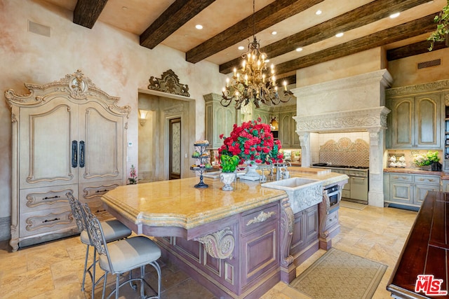 kitchen featuring a towering ceiling, beamed ceiling, light stone counters, decorative backsplash, and a kitchen island with sink