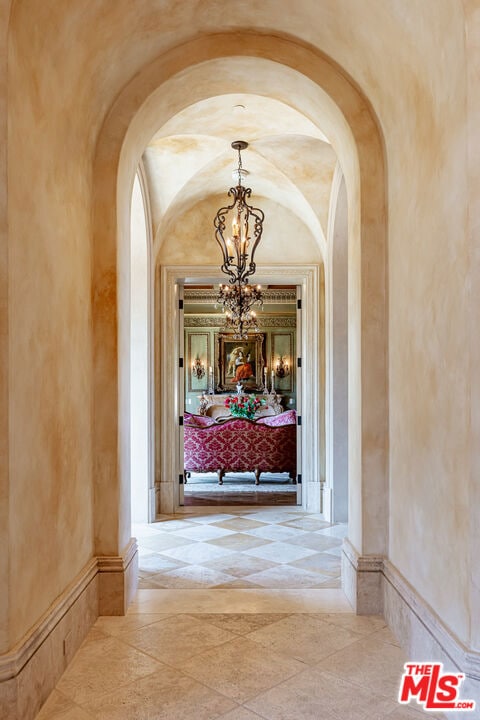 hallway with lofted ceiling and a chandelier