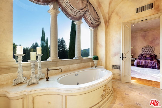 bathroom featuring a bathing tub, tile patterned floors, and ornate columns