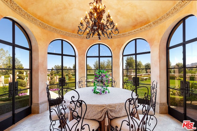 sunroom / solarium featuring plenty of natural light, french doors, and a chandelier