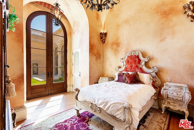 bedroom with french doors, light hardwood / wood-style flooring, an inviting chandelier, and access to outside