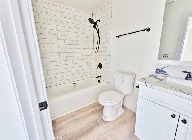 full bathroom featuring toilet, tiled shower / bath combo, wood-type flooring, and vanity