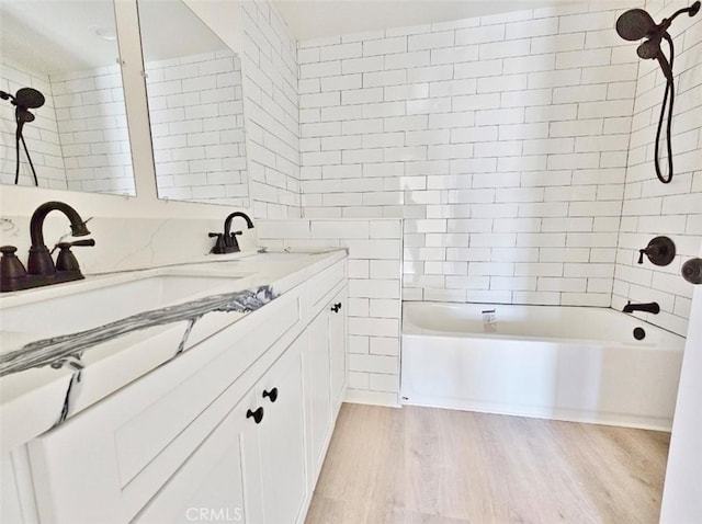 bathroom with hardwood / wood-style floors, vanity, and tiled shower / bath