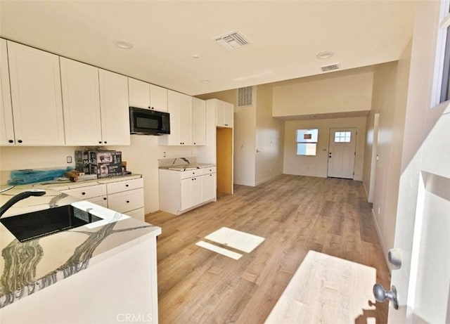 kitchen featuring white cabinets, light wood-type flooring, and sink