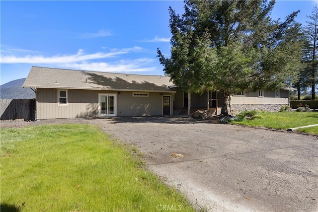 back of property with a lawn and fence