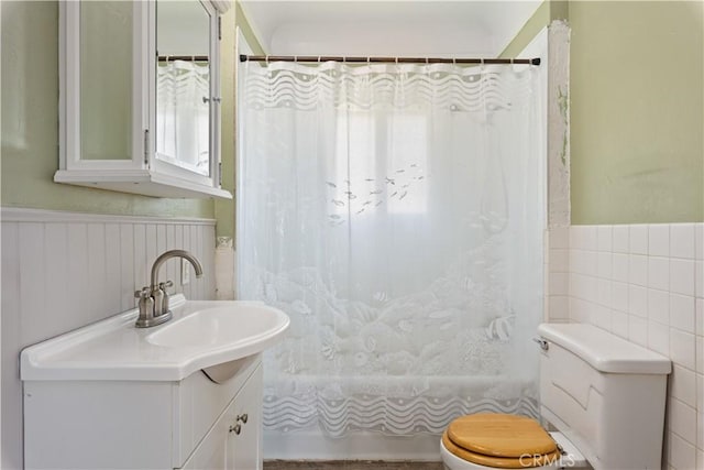 bathroom featuring vanity, toilet, shower / tub combo with curtain, and wainscoting