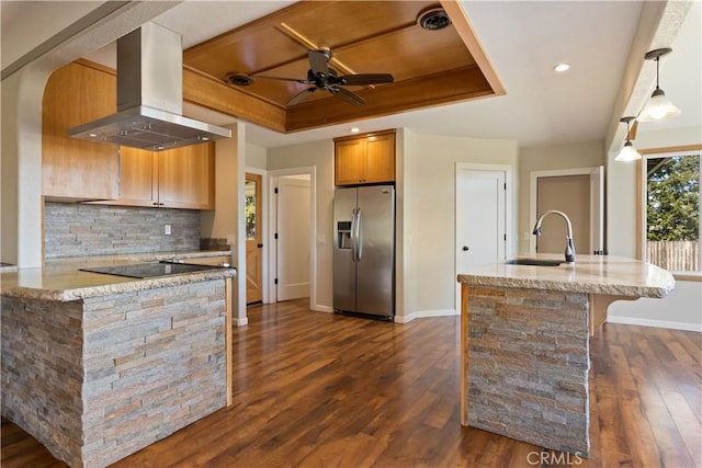 kitchen with decorative backsplash, island exhaust hood, stainless steel fridge, a raised ceiling, and a sink