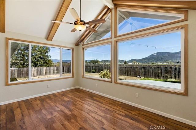 unfurnished sunroom with lofted ceiling with beams, a ceiling fan, and a mountain view