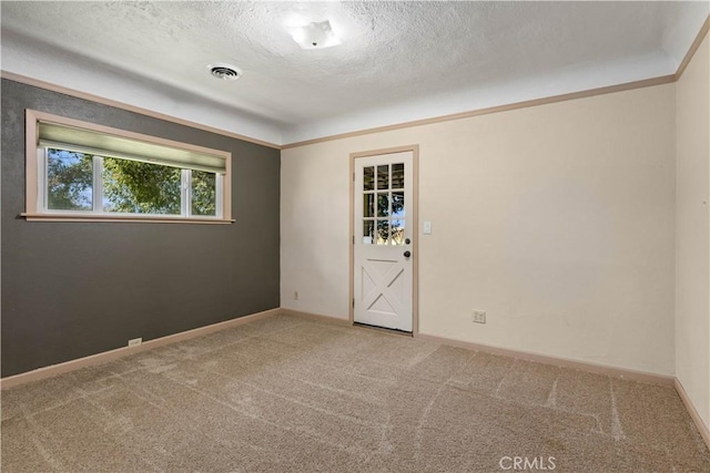 carpeted empty room with visible vents, baseboards, and a textured ceiling