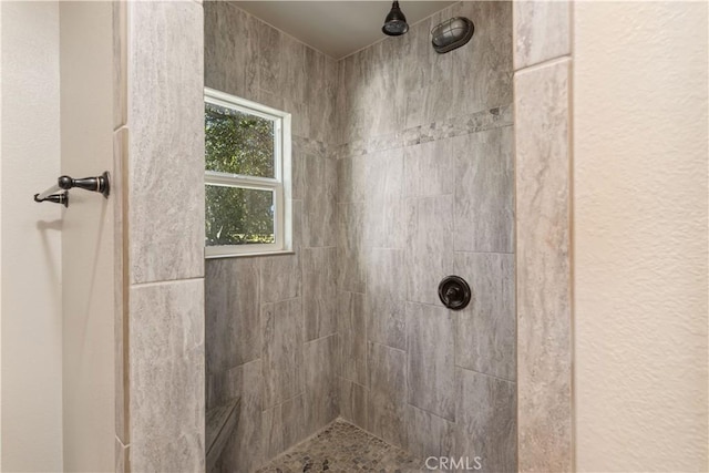 bathroom featuring tiled shower and a textured wall