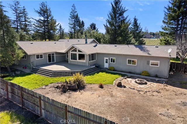 back of house featuring a yard, fence, and an outdoor fire pit