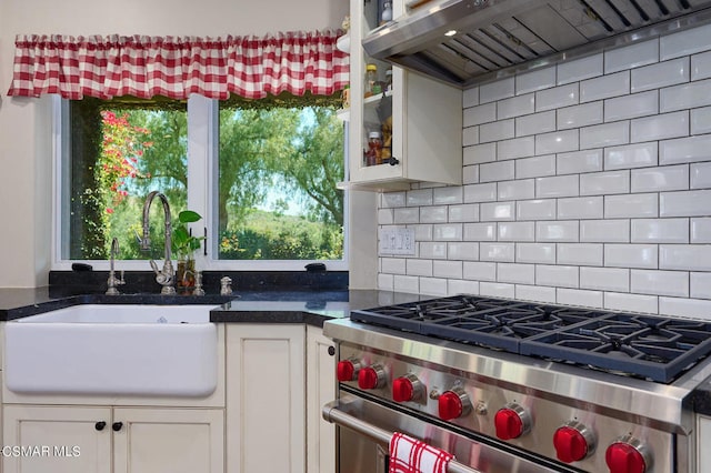 kitchen with exhaust hood, sink, stainless steel range, tasteful backsplash, and white cabinetry