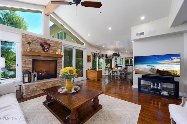 living room with plenty of natural light, a stone fireplace, dark hardwood / wood-style flooring, and high vaulted ceiling