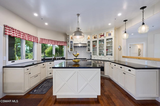 kitchen featuring kitchen peninsula, stainless steel oven, dark wood-type flooring, decorative light fixtures, and white cabinetry