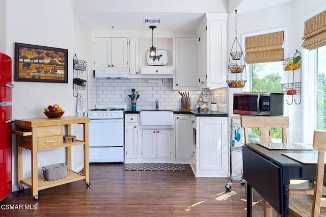 kitchen with sink, hanging light fixtures, dark hardwood / wood-style flooring, white cabinets, and white stove