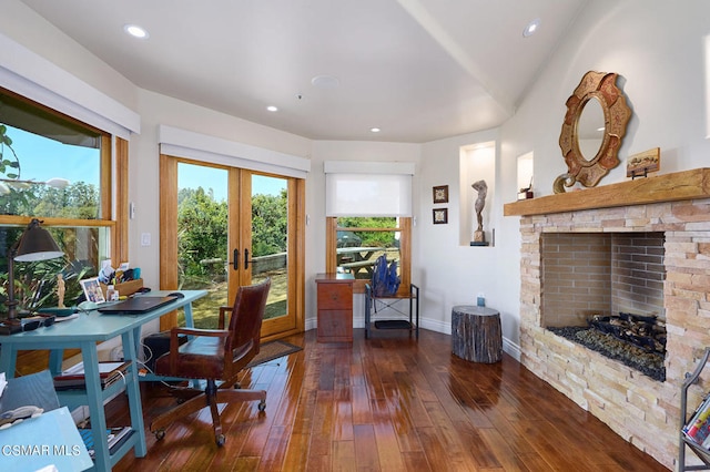 office area with dark hardwood / wood-style floors, a stone fireplace, and french doors